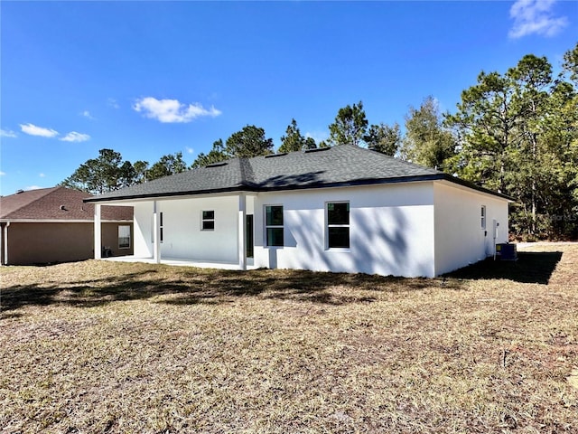 back of house with central AC, roof with shingles, and stucco siding