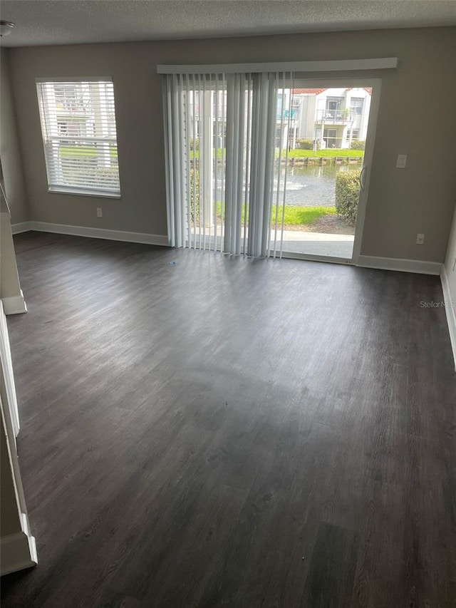 spare room featuring plenty of natural light, dark wood-style flooring, and a textured ceiling