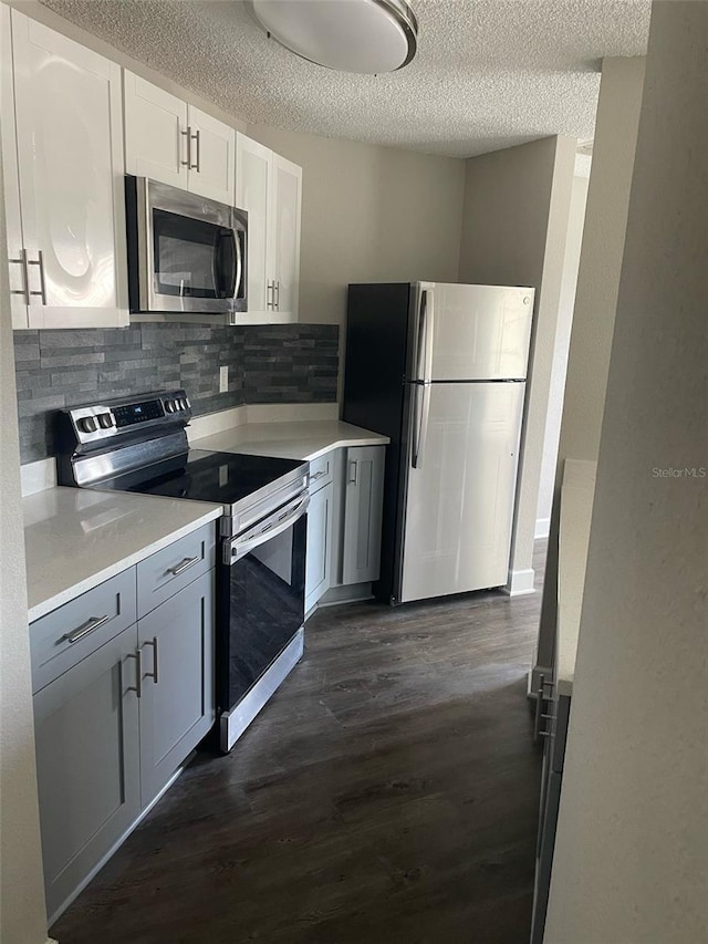 kitchen with stainless steel appliances, dark wood finished floors, light countertops, and white cabinetry