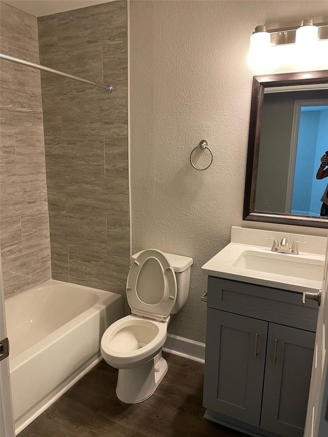 full bath featuring baseboards, a textured wall, toilet, wood finished floors, and vanity