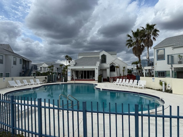 community pool with a residential view, a patio area, and fence