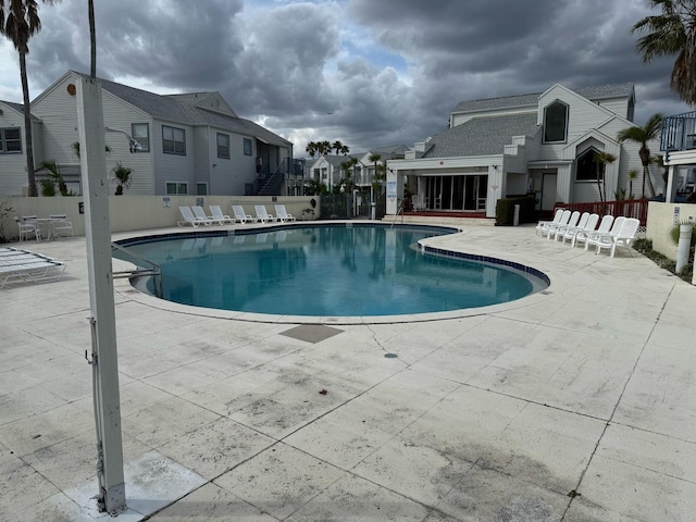 pool with a patio area, fence, and a residential view