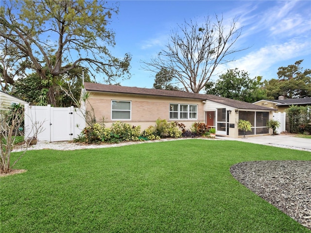 ranch-style house with concrete driveway, a front yard, a gate, and a sunroom