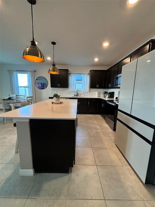 kitchen featuring refrigerator, light tile patterned flooring, a kitchen island, range with electric stovetop, and hanging light fixtures