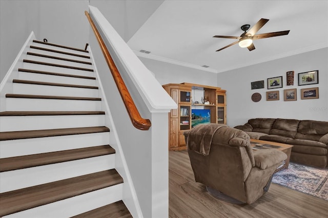 living room featuring ceiling fan, ornamental molding, stairway, and wood finished floors