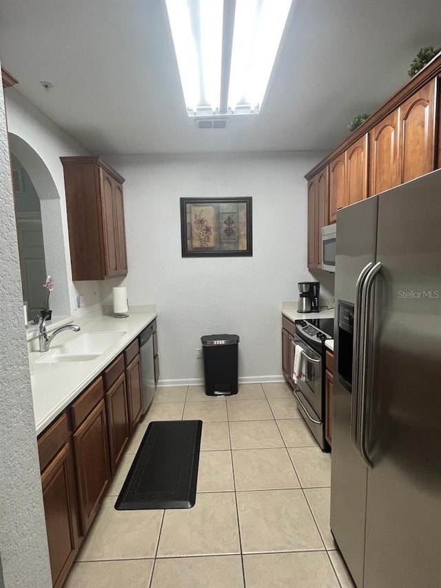 kitchen with light tile patterned floors, stainless steel appliances, a sink, and light countertops