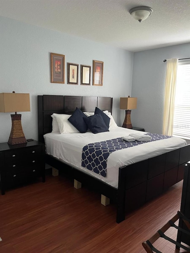 bedroom with a textured ceiling and wood finished floors