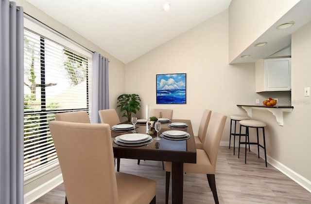 dining space with lofted ceiling, light wood-type flooring, and baseboards