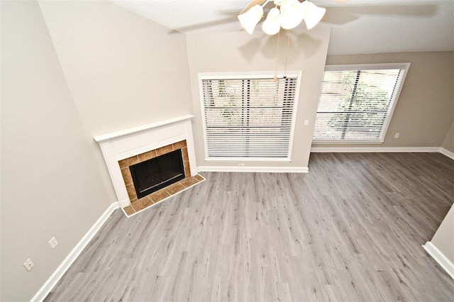 unfurnished living room with light wood-style floors, a fireplace, baseboards, and ceiling fan