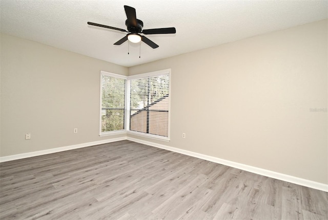 empty room featuring a ceiling fan, light wood-style flooring, baseboards, and a textured ceiling