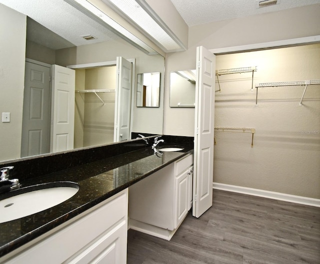 bathroom with double vanity, wood finished floors, a sink, and visible vents