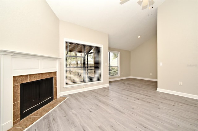 unfurnished living room featuring wood finished floors, a ceiling fan, baseboards, vaulted ceiling, and a tiled fireplace