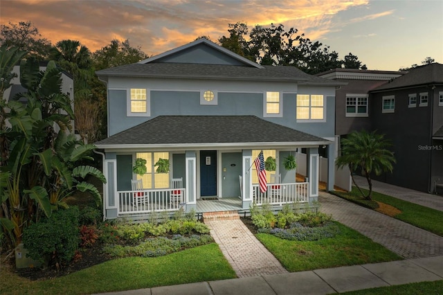 view of front of home featuring covered porch, roof with shingles, and stucco siding