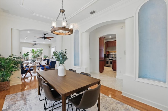 dining room with arched walkways, visible vents, light wood-style flooring, ornamental molding, and baseboards