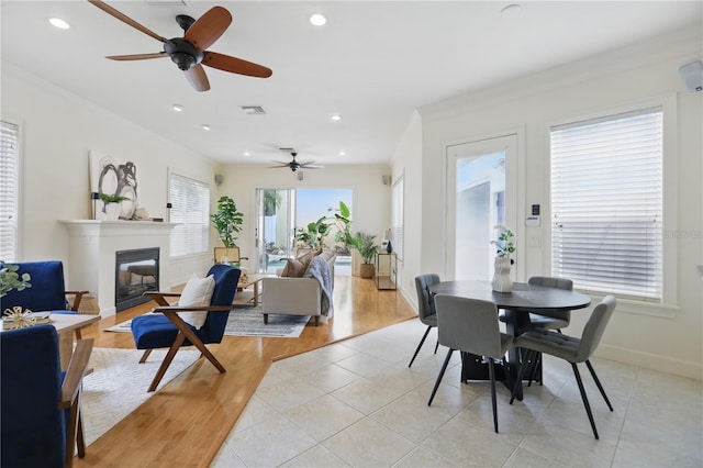 dining area featuring baseboards, visible vents, a glass covered fireplace, crown molding, and recessed lighting