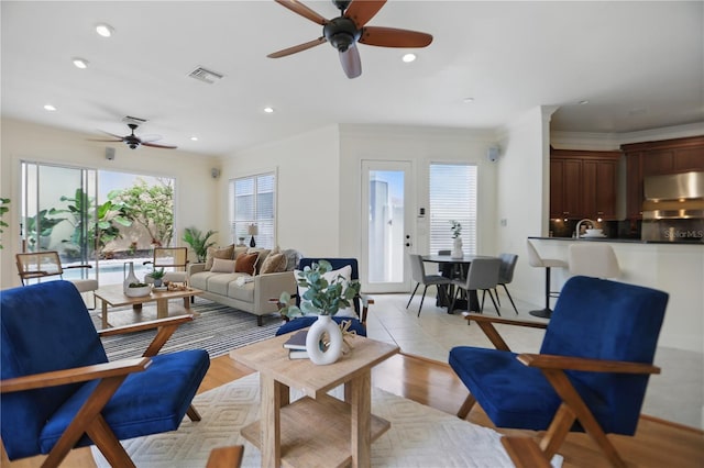 living room featuring a ceiling fan, visible vents, crown molding, and recessed lighting