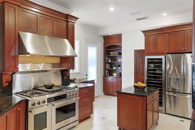 kitchen featuring under cabinet range hood, stainless steel appliances, visible vents, dark stone counters, and crown molding