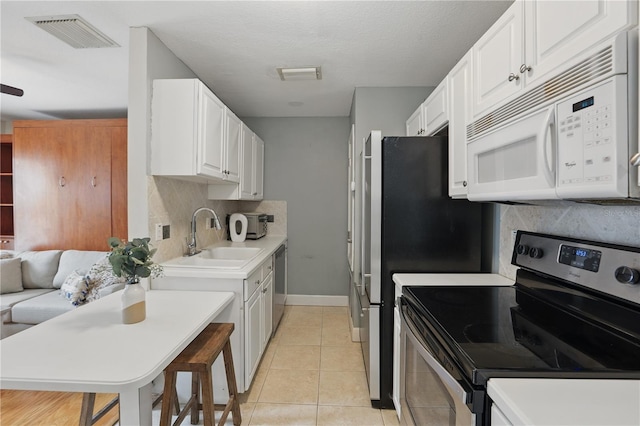 kitchen with visible vents, stainless steel appliances, light countertops, white cabinetry, and a sink