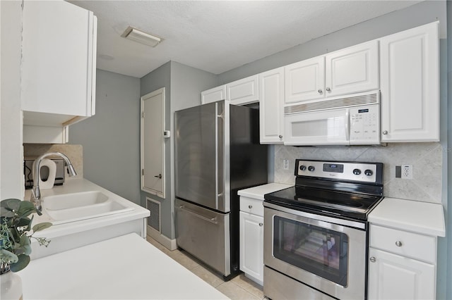 kitchen featuring visible vents, white cabinets, stainless steel appliances, light countertops, and backsplash