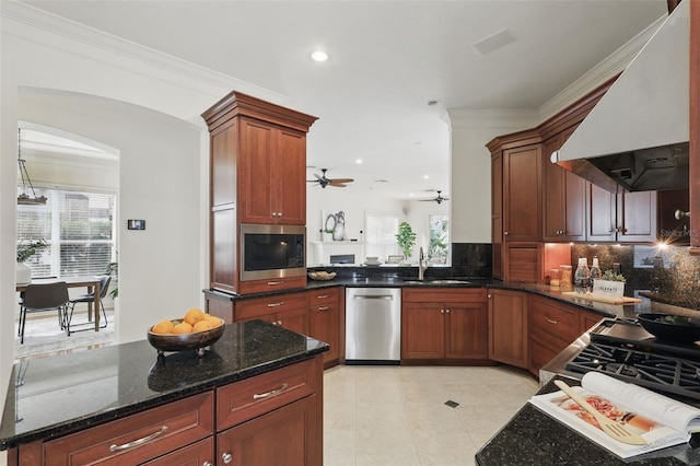 kitchen featuring a sink, range hood, appliances with stainless steel finishes, decorative backsplash, and dark stone counters