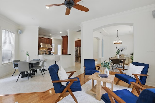 living area with light wood-style floors, baseboards, arched walkways, and ornamental molding