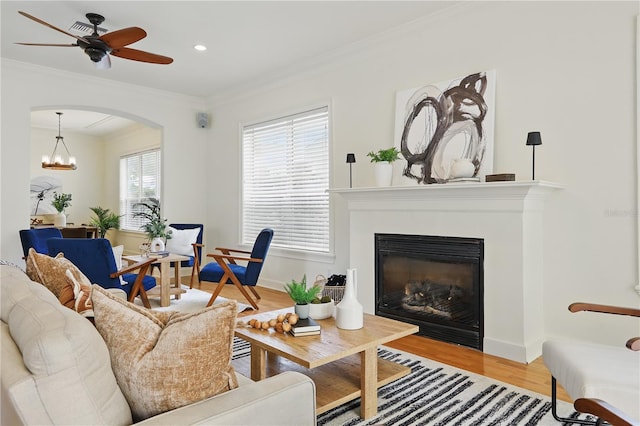 living room with baseboards, a glass covered fireplace, wood finished floors, crown molding, and recessed lighting