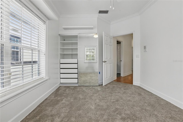 unfurnished bedroom with baseboards, visible vents, crown molding, carpet floors, and a closet