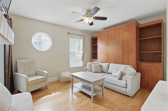 living area with ceiling fan, light wood-style flooring, and baseboards