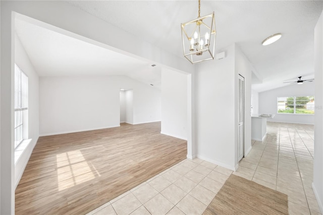 unfurnished room with light tile patterned flooring, vaulted ceiling, baseboards, and ceiling fan with notable chandelier