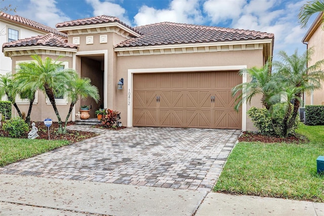 mediterranean / spanish house with a garage, decorative driveway, and stucco siding