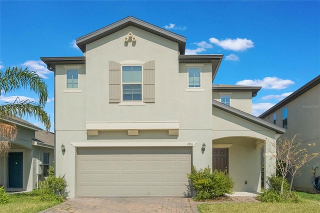 view of front of property with a garage, decorative driveway, and stucco siding