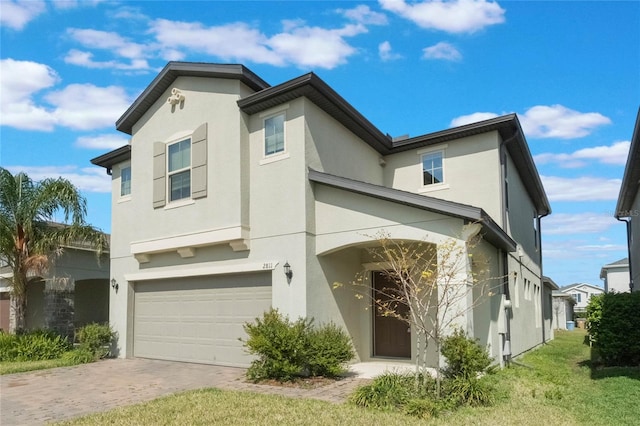 view of front of home with driveway, a front yard, an attached garage, and stucco siding