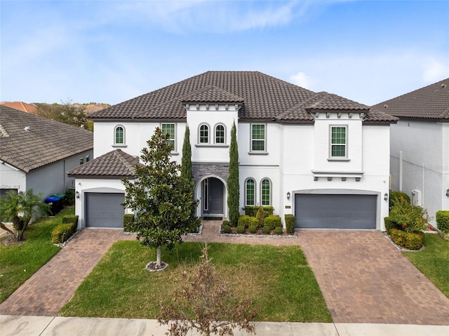 mediterranean / spanish house with a garage, a front yard, decorative driveway, and a tile roof