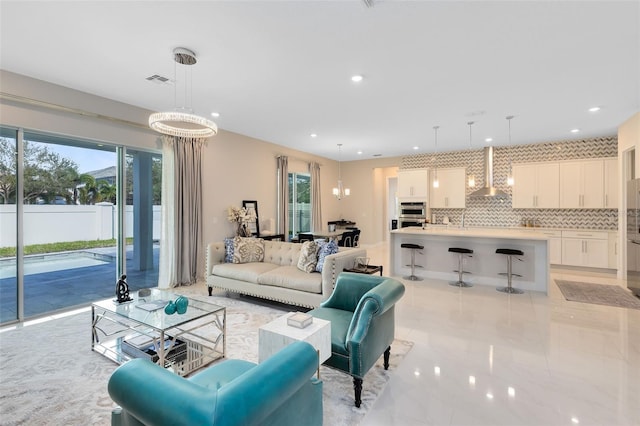 living area featuring an inviting chandelier, visible vents, and a healthy amount of sunlight