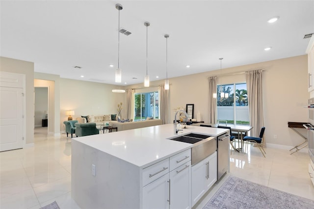 kitchen with a kitchen island with sink, a sink, white cabinetry, light countertops, and pendant lighting