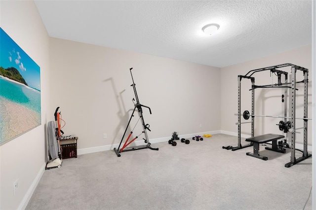 workout room with a textured ceiling, carpet, and baseboards