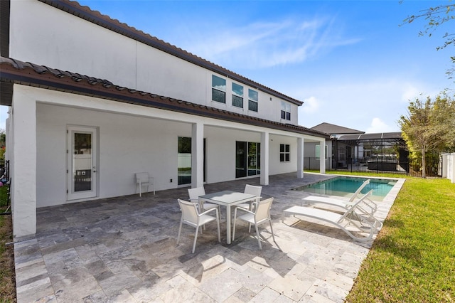 rear view of property with a patio, glass enclosure, a tile roof, a fenced in pool, and stucco siding