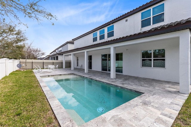 back of house featuring a fenced backyard, a tile roof, a yard, a patio area, and stucco siding