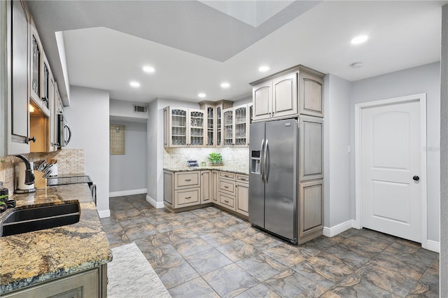 kitchen featuring visible vents, glass insert cabinets, a sink, stainless steel appliances, and backsplash