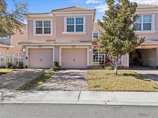 view of front of home with a garage, decorative driveway, a tiled roof, and stucco siding