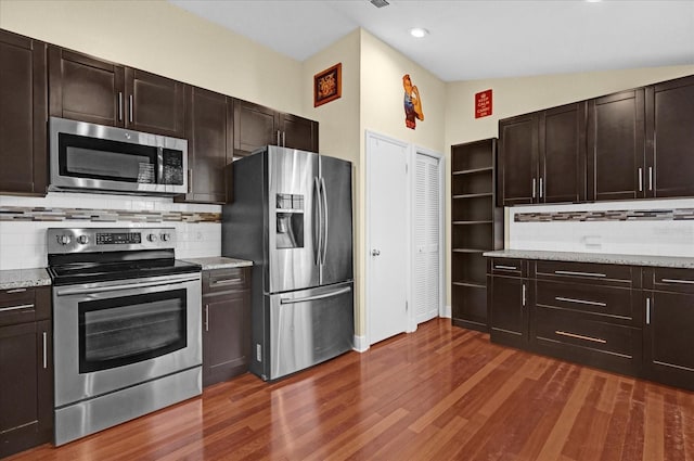 kitchen featuring light stone counters, stainless steel appliances, and dark brown cabinets