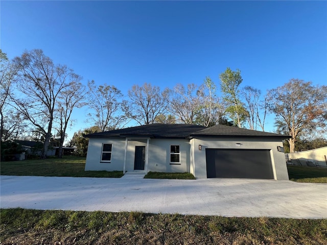 view of front facade with a front lawn, concrete driveway, an attached garage, and stucco siding