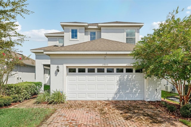 view of front of home with a garage, roof with shingles, decorative driveway, and stucco siding