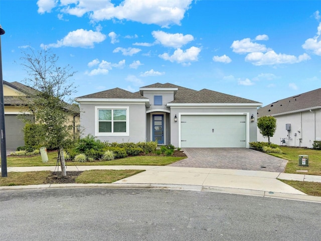 prairie-style house featuring a garage, decorative driveway, a front yard, and stucco siding