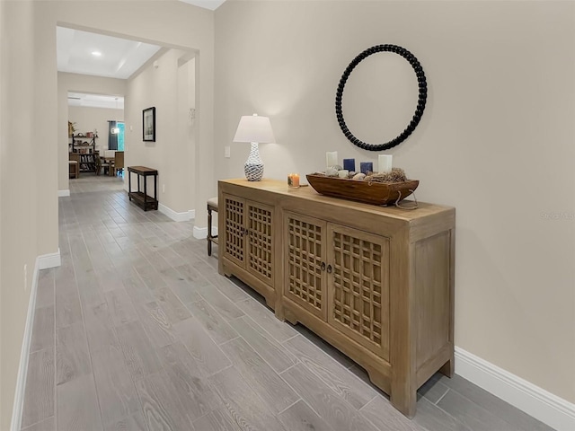 hallway with light wood-type flooring and baseboards