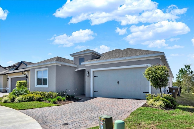 prairie-style home with decorative driveway, an attached garage, and stucco siding