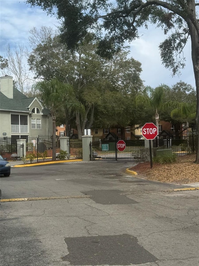 view of street featuring curbs, a gated entry, traffic signs, and a gate