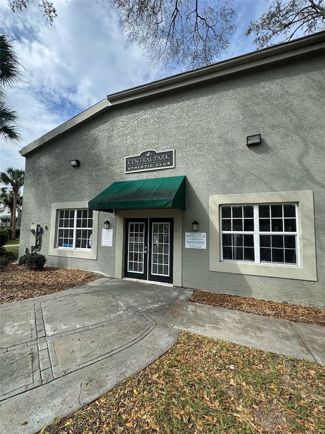 view of exterior entry featuring french doors and stucco siding