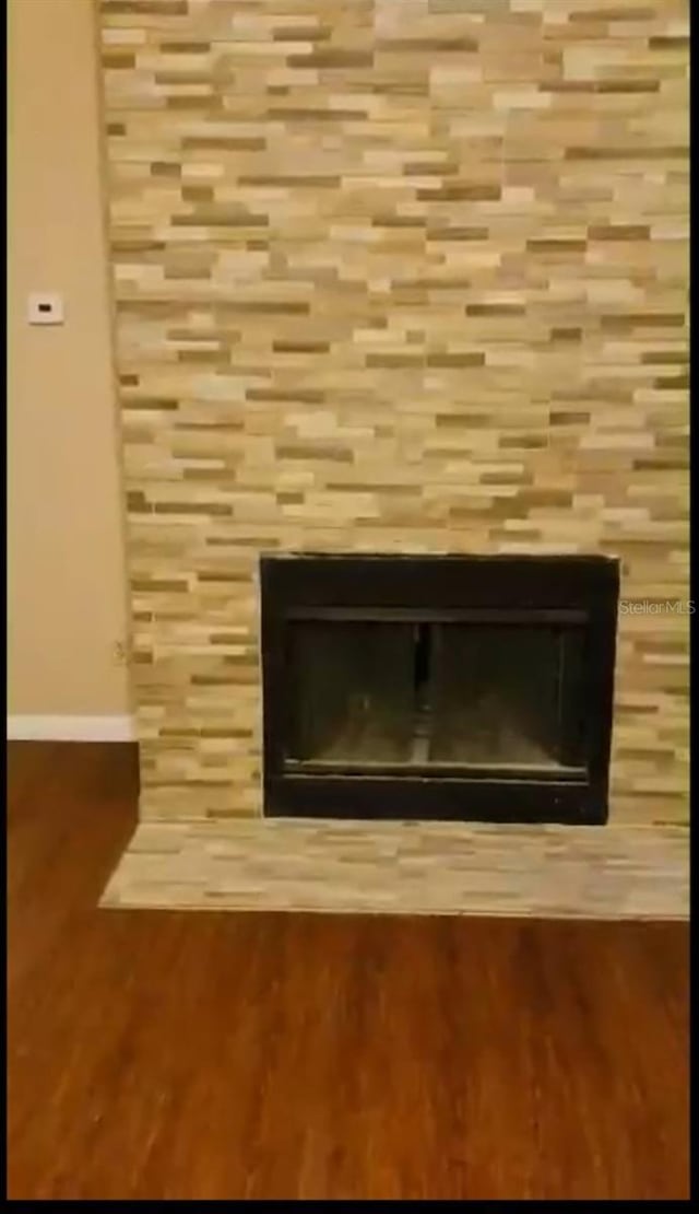 details featuring a tile fireplace, wood finished floors, and baseboards