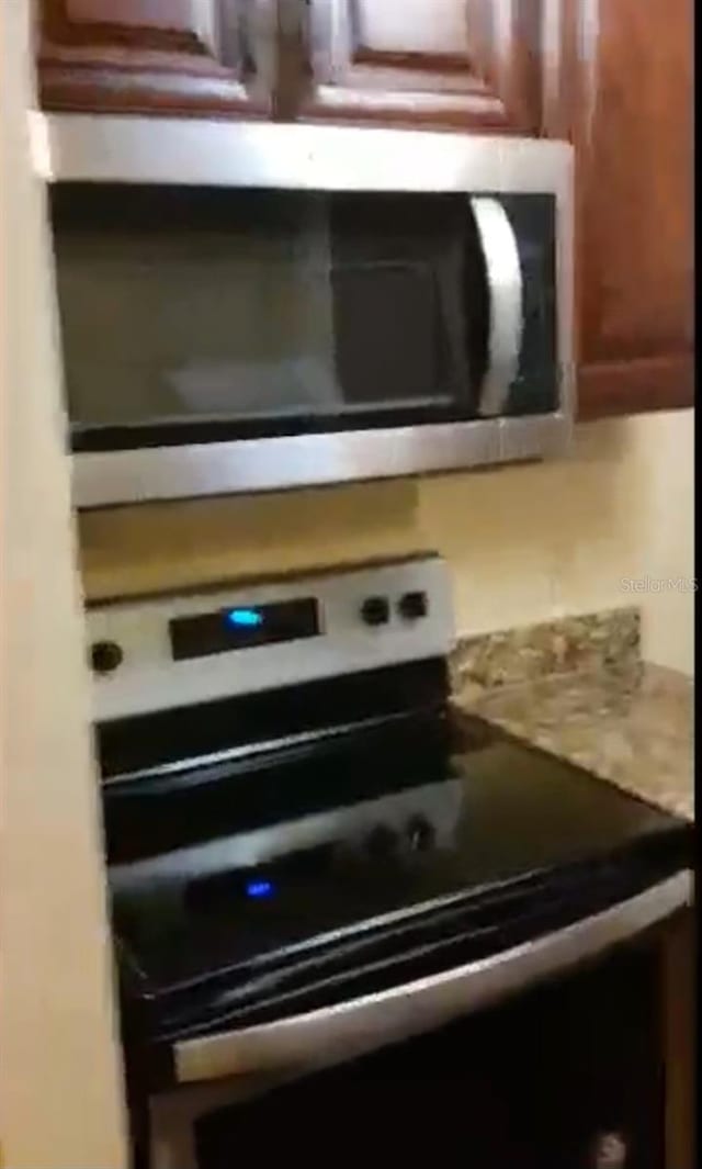 details featuring appliances with stainless steel finishes and brown cabinets